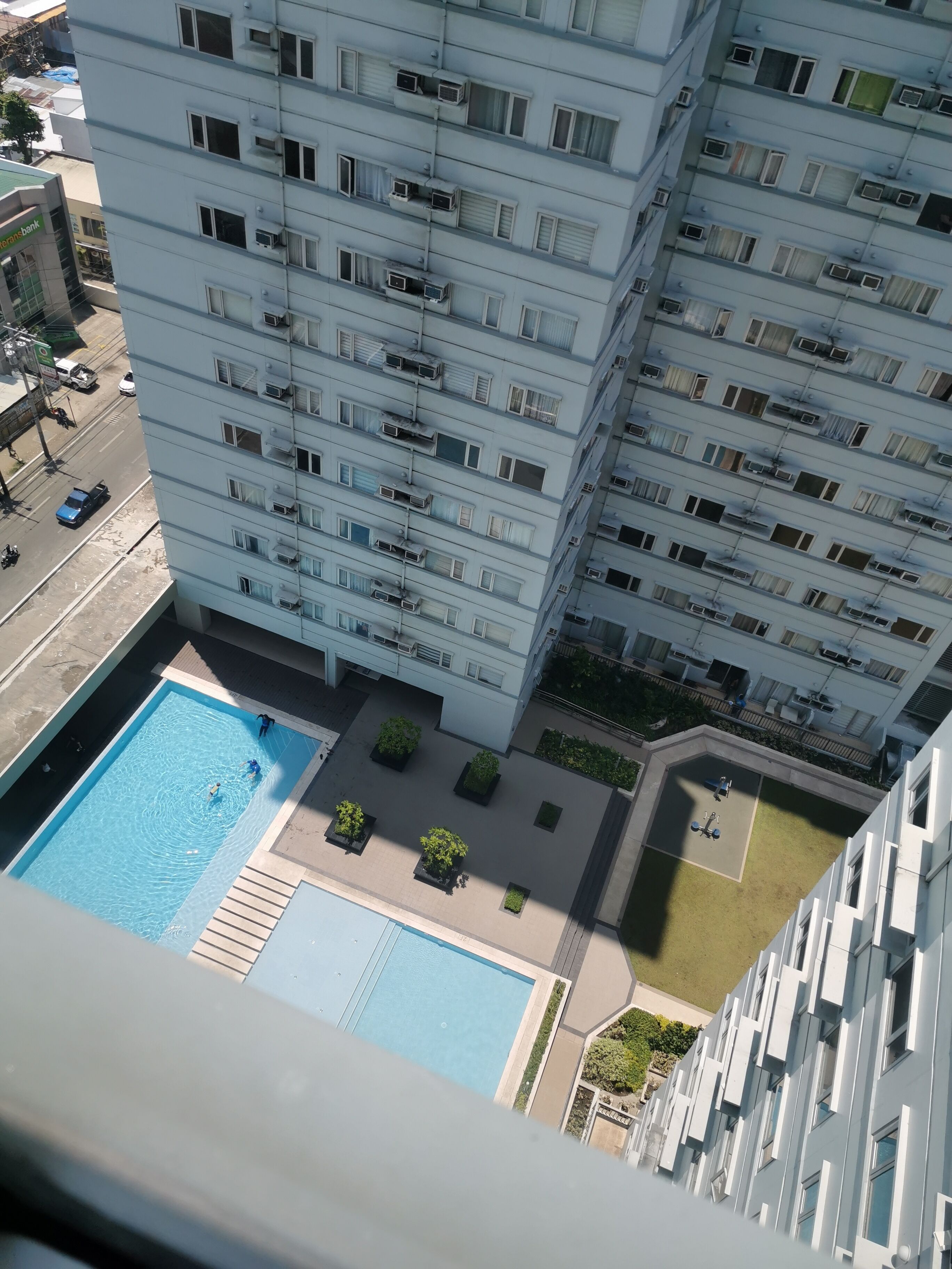 Un immeuble de grande hauteur doté de nombreux balcons, d’une piscine et d’un petit jardin.