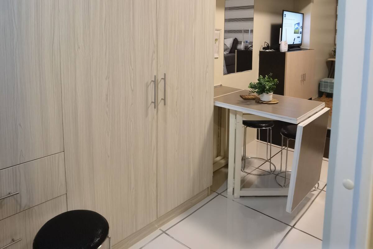 Kompakti keittiö, jossa on pieni ruokailutila, sisäänrakennettu televisio ja ikkuna.
