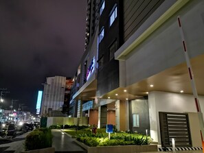 Un hôtel moderne à la façade sobre, doté de grandes fenêtres et d’une entrée bien éclairée.