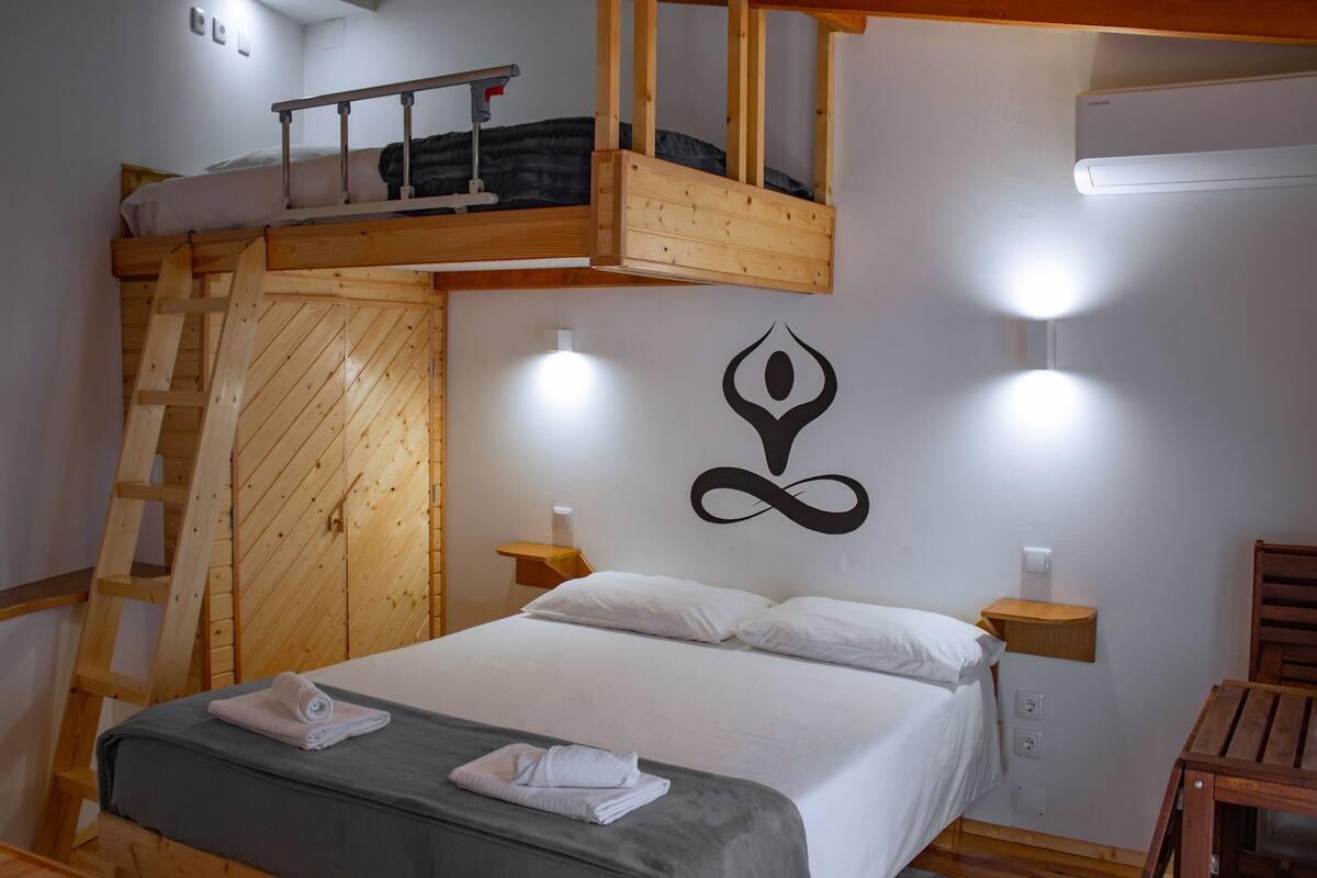 Un dormitorio con una cama litera, una escalera de madera, un símbolo en la pared y lámparas de noche.