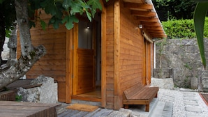 Une cabane en bois avec une porte en bois et un banc à l’extérieur.