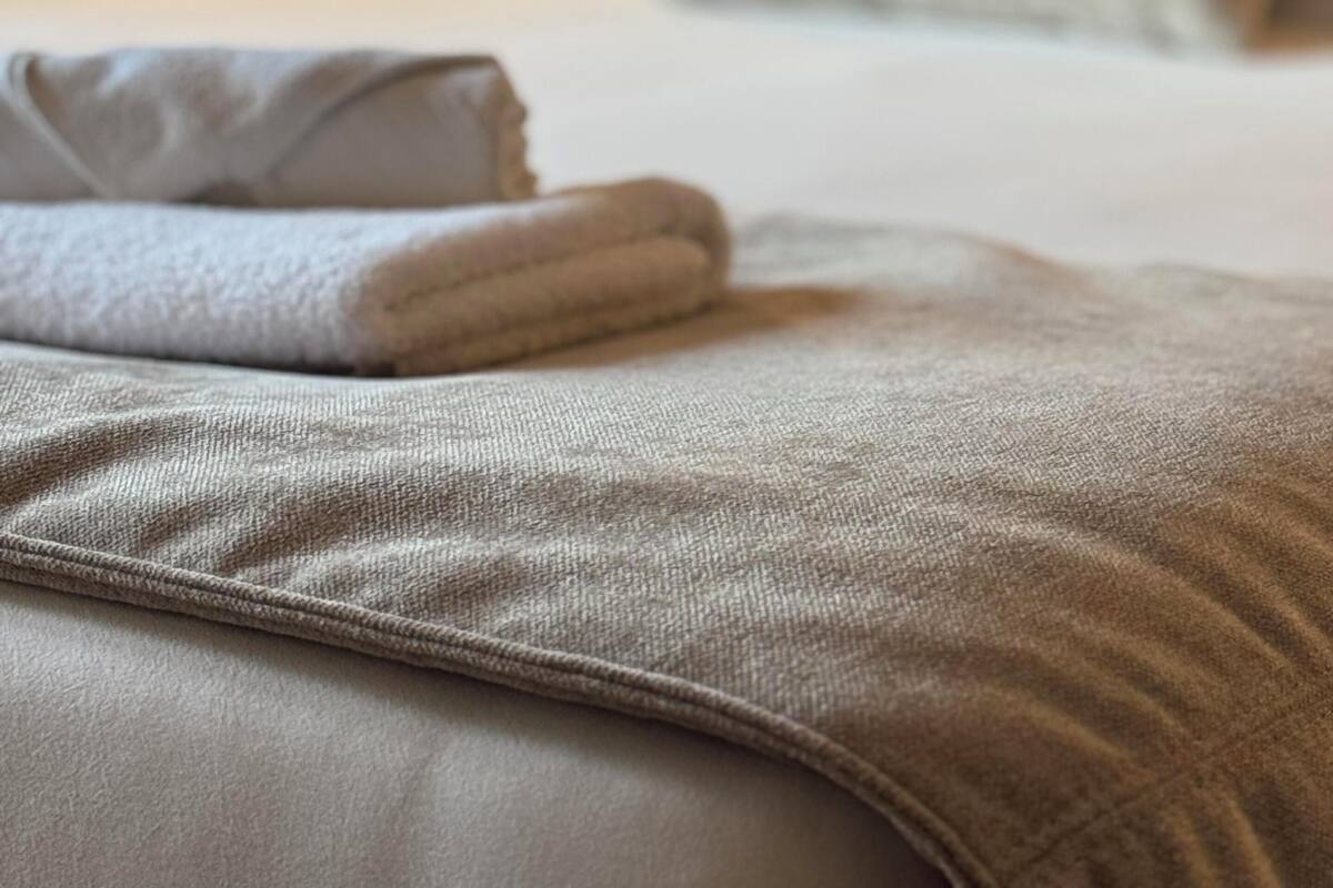 Una cama bien hecha con un almohadón y una manta doblada en una habitación de hotel.