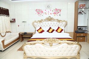 Ein Schlafzimmer mit einem großen Bett, einem Schlafsofa, einem Nachttisch, einem Kleiderschrank und einem Wandventilator.