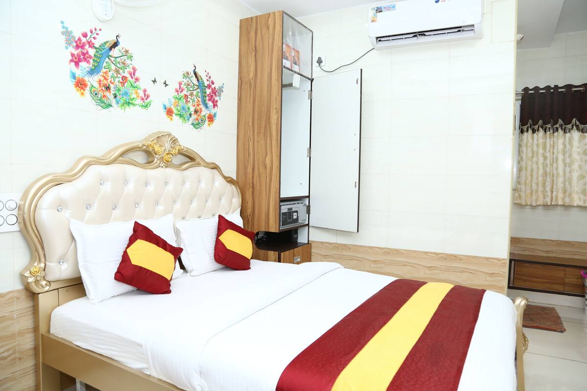 A hotel room with a bed, a wardrobe, a mirror, and a wall-mounted air conditioner.