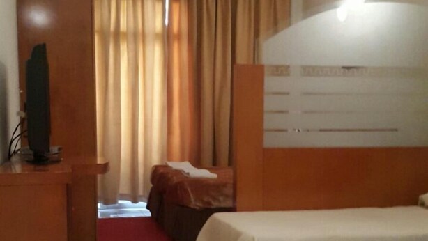 Ein Hotelzimmer mit Bett, Schreibtisch, Stuhl, kleinem Tisch und Mülleimer.