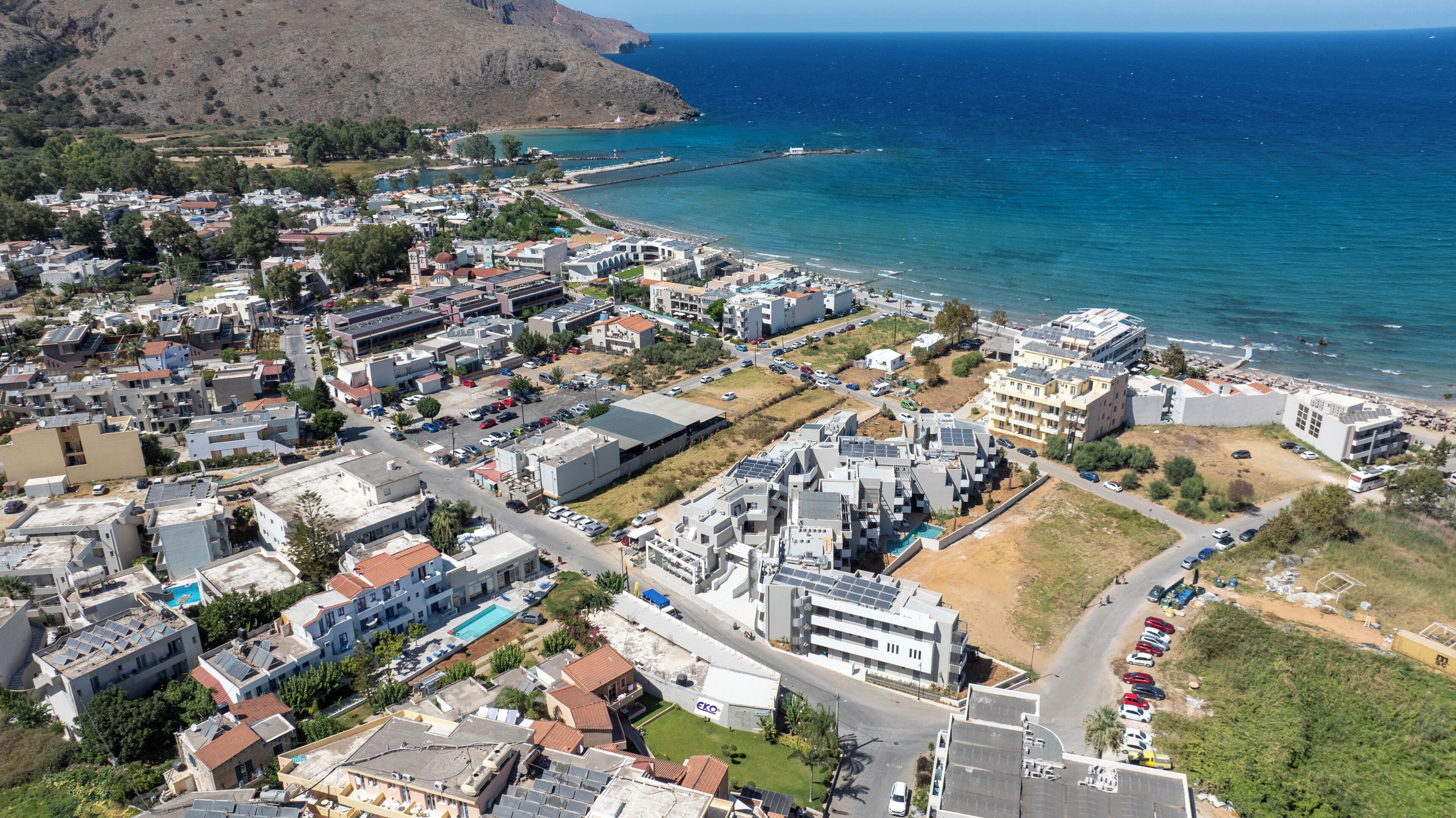 Vista aérea de un pueblo costero con edificios, carreteras y una playa.