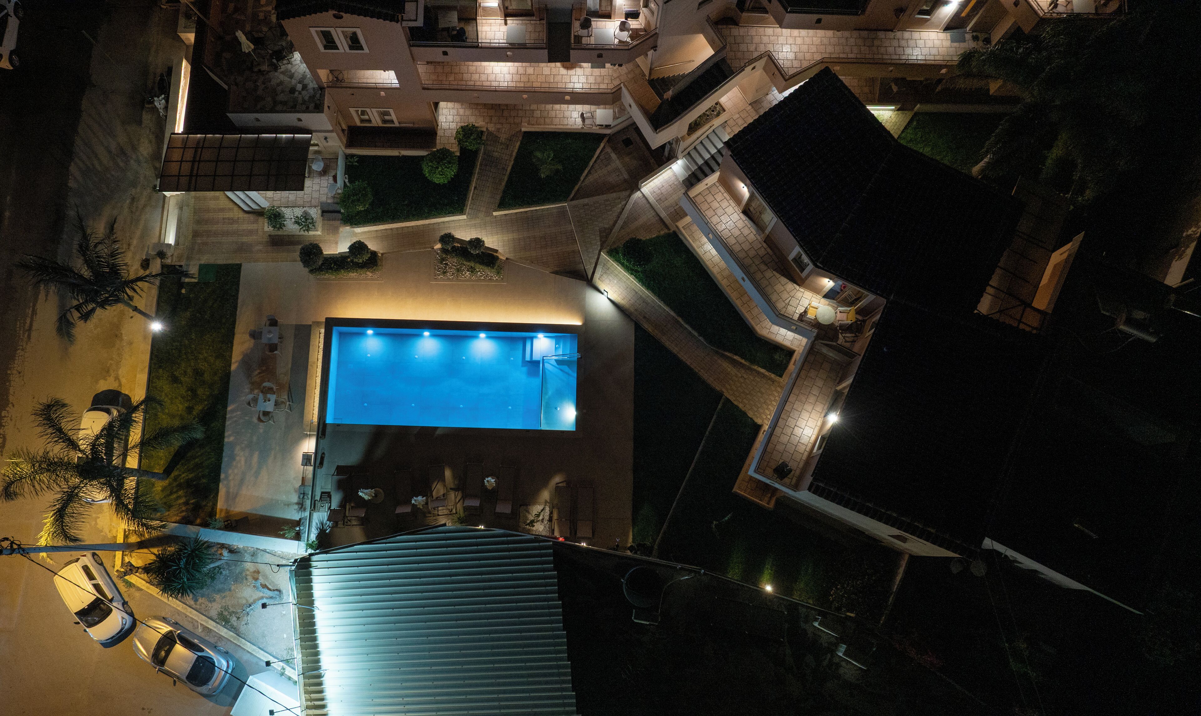 Vista aérea de una zona residencial con piscina, varios edificios y un espacio exterior bien iluminado.