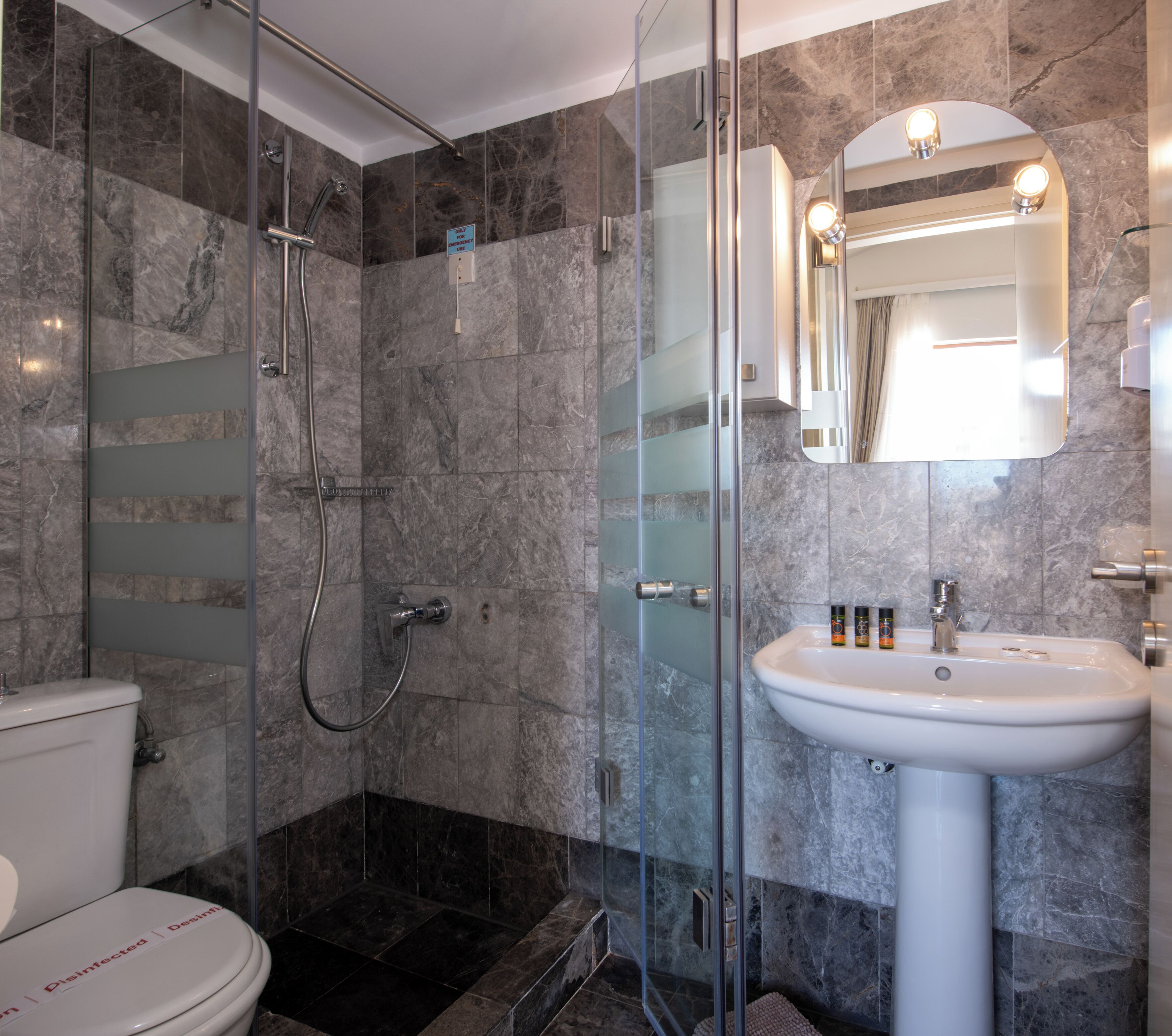 Un baño moderno con ducha envuelta en vidrio, lavamanos blanco y un inodoro.