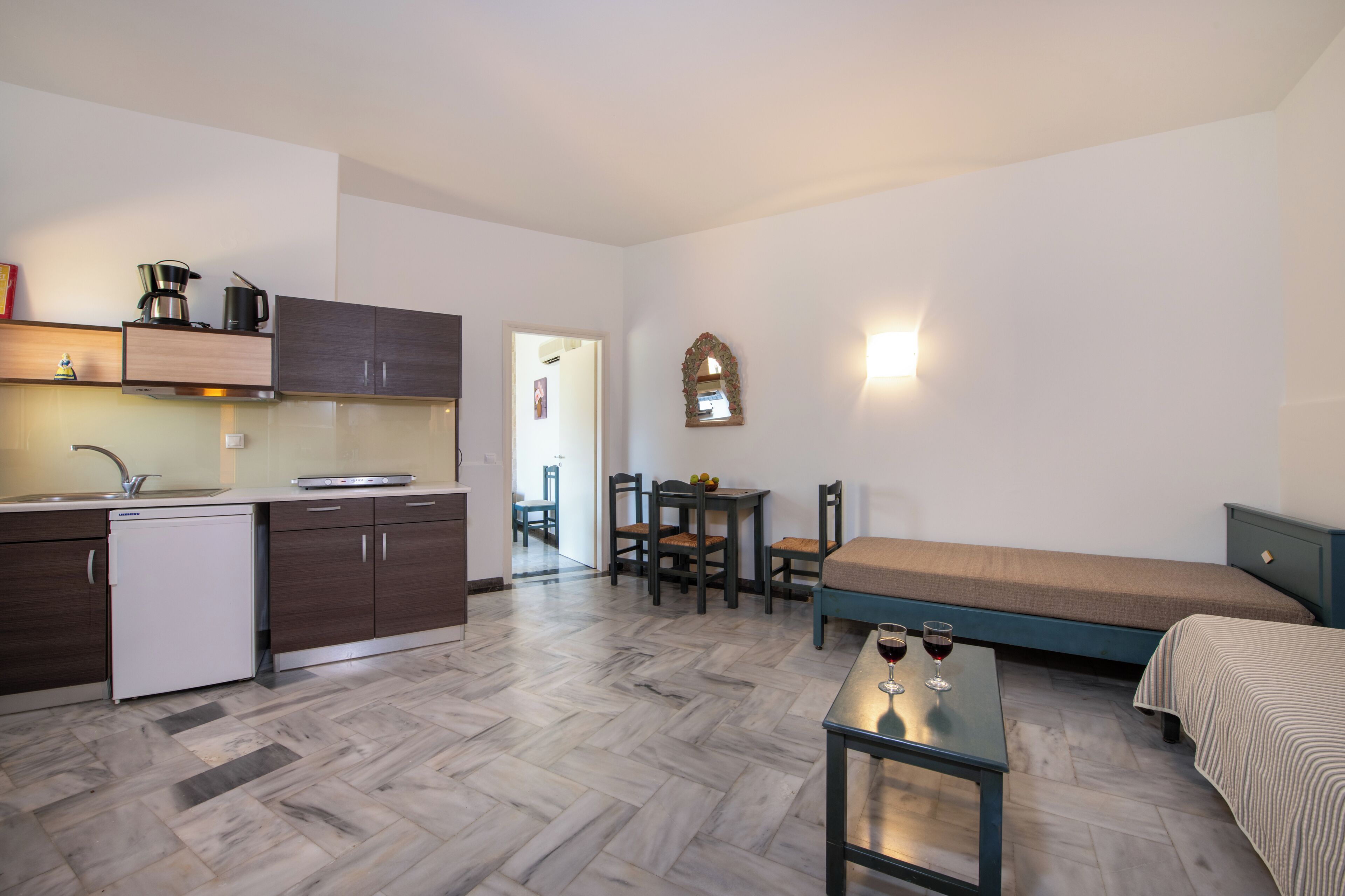 Una habitación compacta con kitchenette, comedor y cama.