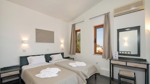 Une chambre d’hôtel avec deux lits, un bureau, une chaise, un miroir et une fenêtre avec des rideaux.