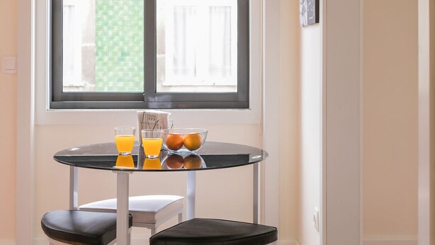 Ein kleiner Tisch mit zwei Stühlen, einer Obstschale und zwei Gläsern Orangensaft.