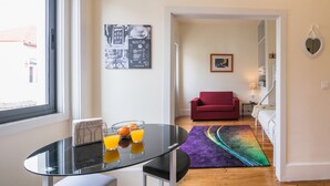 Ein modernes Wohnzimmer mit einem Glastisch, einem roten Sofa und einem farbenfrohen Teppich.