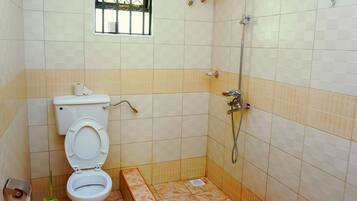 A small bathroom with a toilet, a shower, and a window.