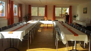 A conference room with long tables, chairs, and large windows with curtains. - Sefano Seminarfabrik Nossen (Nossen)