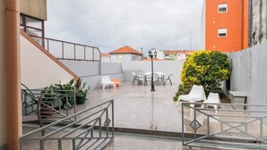 Une terrasse sur le toit, dotée d’un espace extérieur aménagé avec des sièges, d’un escalier et offrant une vue sur les bâtiments environnants.