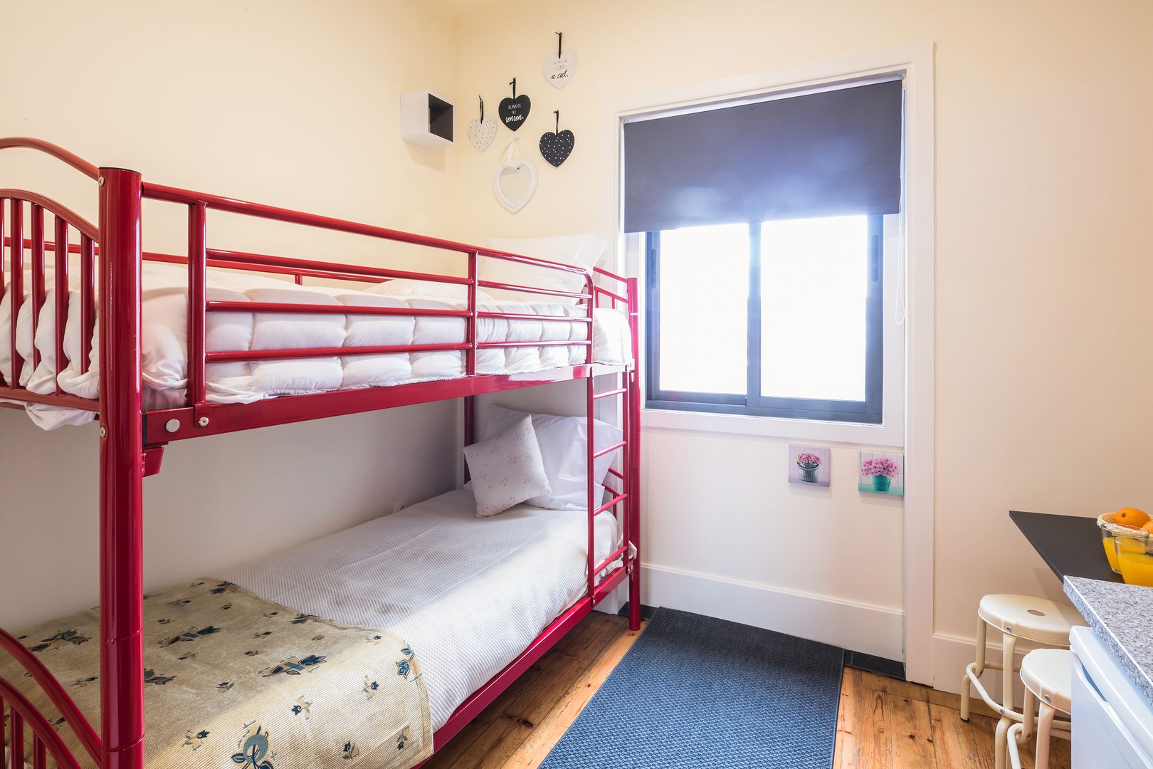 A bunk bed room with a window, a small desk, and a chair.