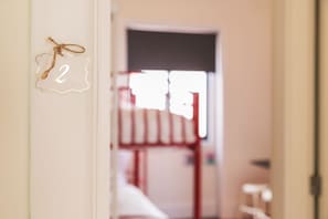 Une porte marquée du numéro « 2 », qui donne sur une pièce contenant un lit et une fenêtre.