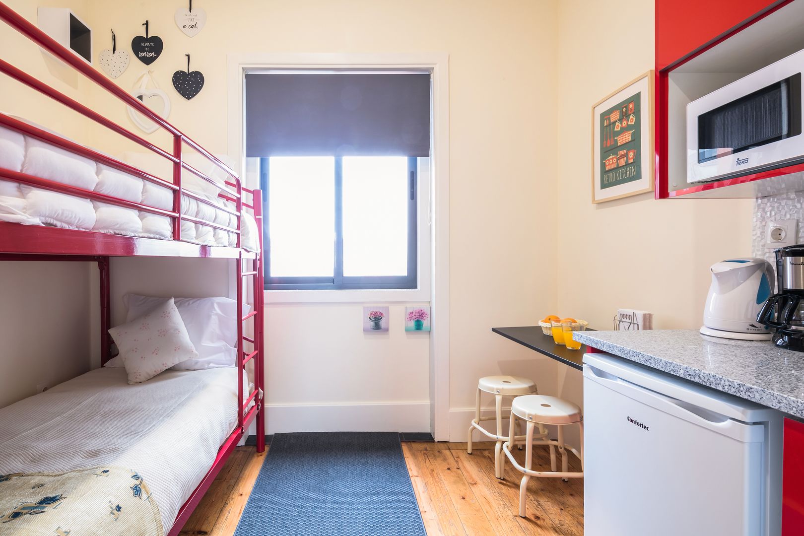 A compact room with bunk beds, a kitchenette, and a small window.