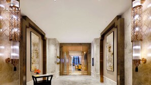 Un hall d’hôtel doté d’un sol en marbre, d’un comptoir de réception et de luminaires fixés aux murs.