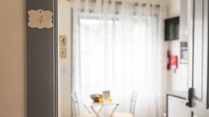 Ein Zimmer mit einem Esstisch und Stühlen, einem kleinen Tisch mit Schüssel und Glas sowie einem Schild mit der Nummer 4 an der Wand.