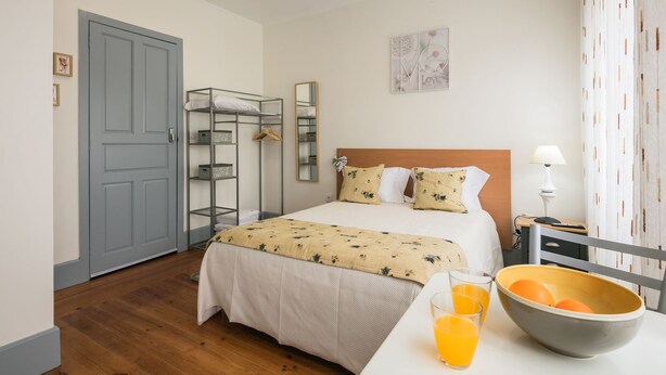 Ein Hotelzimmer mit Bett, Kleiderschrank, Spiegel, Nachttisch mit Lampe und Obstschale.