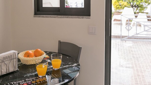 Een eettafel met een mand sinaasappels en twee glaasjes sinaasappel, een servet houder en een bord met het Times Square adres.