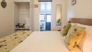 Een hotelkamer met een bed, een kledingkast, een spiegel en een deur naar een balkon.