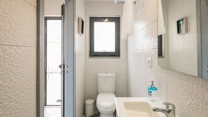 Een kleine badkamer met toilet, wastafel en een klein raam.