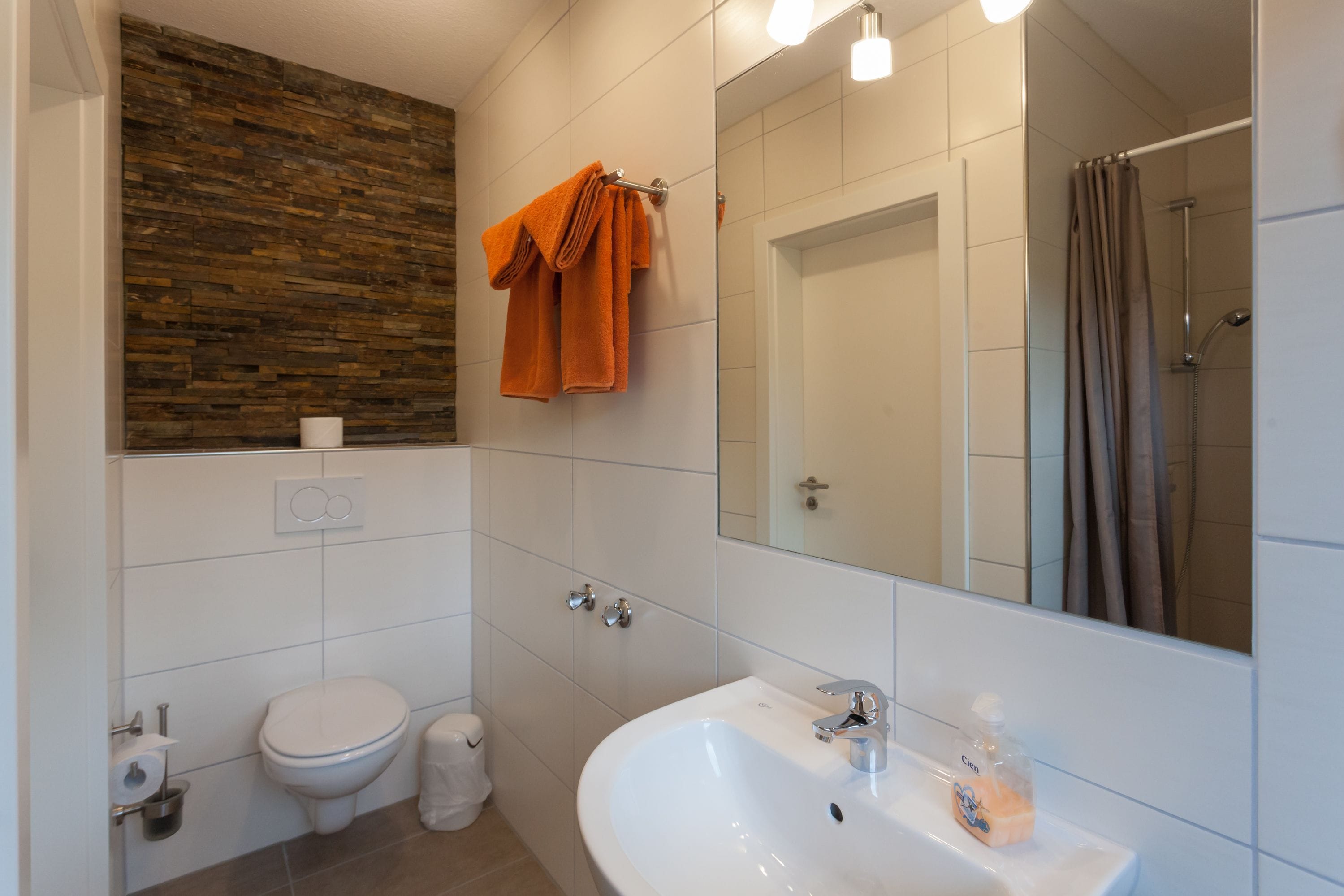 A bathroom with a white sink, a toilet, a mirror, and a shower curtain.