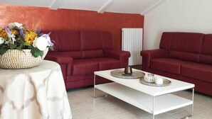 Un salon moderne avec deux canapés rouges, une table basse blanche et une plante décorative posée sur une table ronde.