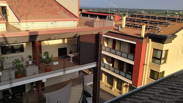 Un immeuble résidentiel à plusieurs étages, doté de balcons, d’un espace extérieur aménagé et couvert, et offrant une vue sur le quartier environnant.