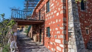A stone building with a red facade, a stone staircase, and a metal bridge. - Stone made Mansions (Apokoronas)