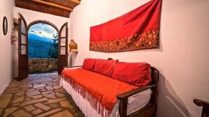 A cozy room with a wooden bench, a red tapestry, and a stone wall. - Stone made Mansions (Apokoronas)