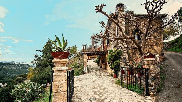 A stone pathway leading to a rustic stone building with a balcony, surrounded by greenery and a mountainous landscape. - Stone made Mansions (Apokoronas)