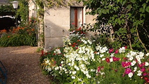 A stone building with a garden in front, featuring a variety of flowers and plants. - Chambres d'hôtes Côté Jardin (Villiers-sur-Loir)