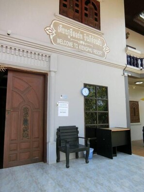 A sign welcoming visitors to Kingphu Resort, with a traditional wooden door and a bench outside.