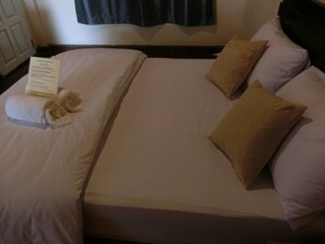 A neatly made bed with white linens and two beige pillows.