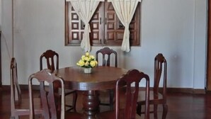 Un comedor con una mesa y sillas de madera, una araña y cuadros en las paredes.