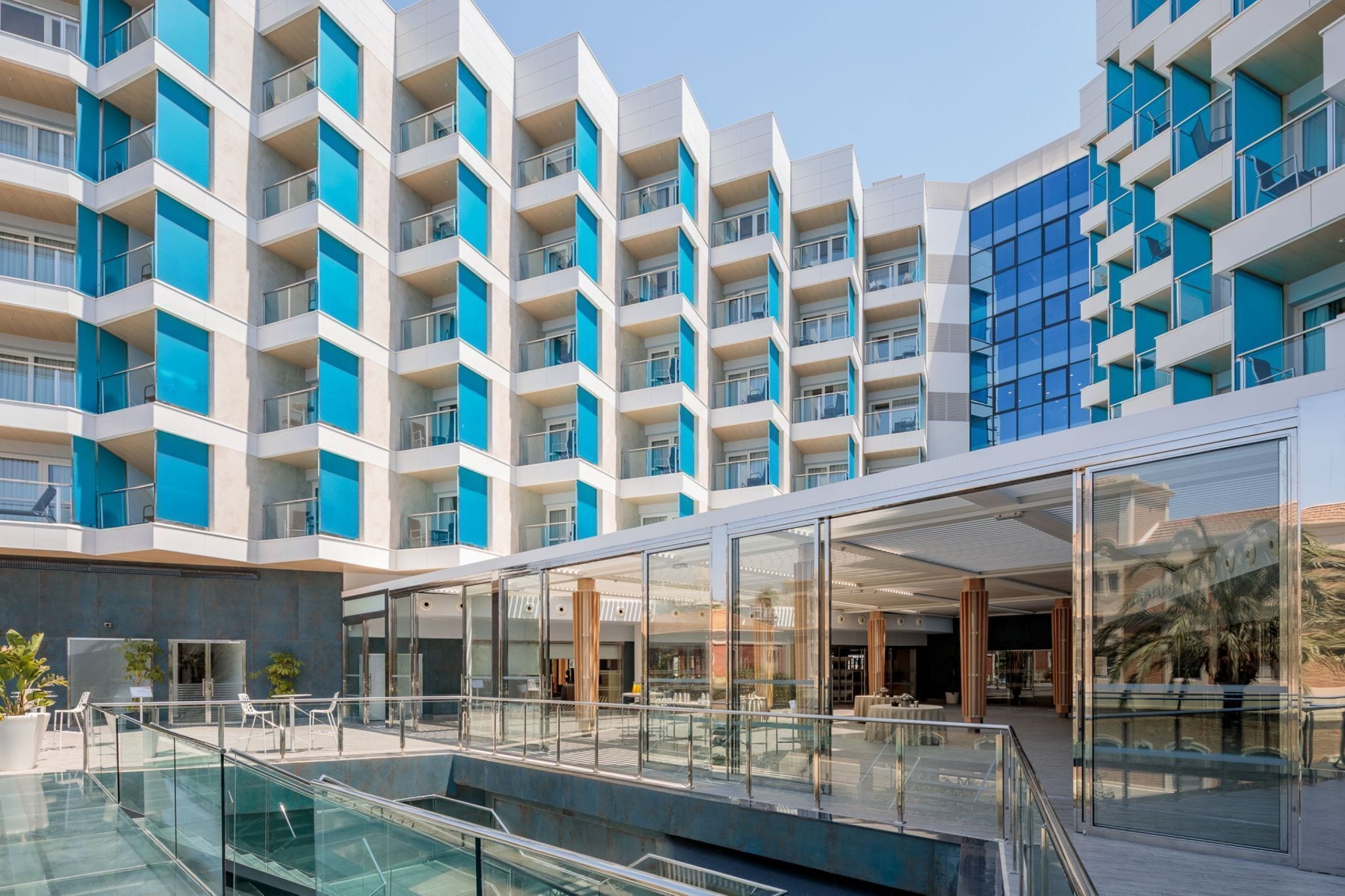 Un hôtel moderne doté de nombreux balcons, d’une piscine et d’un espace extérieur couvert.