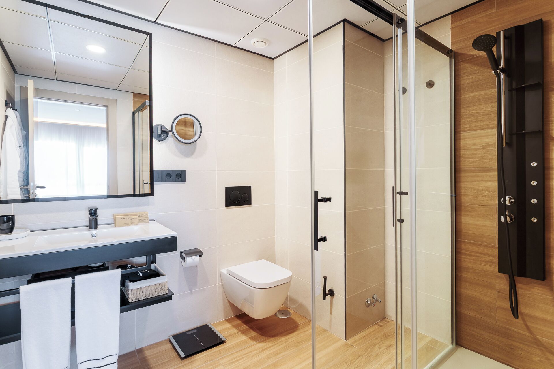 A modern bathroom with a glass shower enclosure, a white toilet, and a vanity with a mirror and sink.
