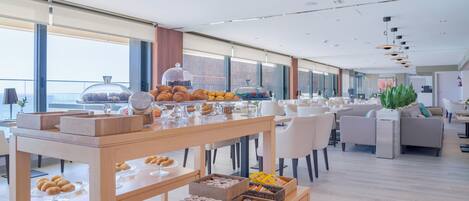 A modern hotel lobby with a buffet area featuring pastries, sandwiches, and beverages.