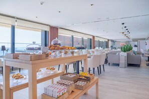 Un hall d'hôtel moderne avec un espace buffet proposant des pâtisseries, des sandwichs et des boissons.