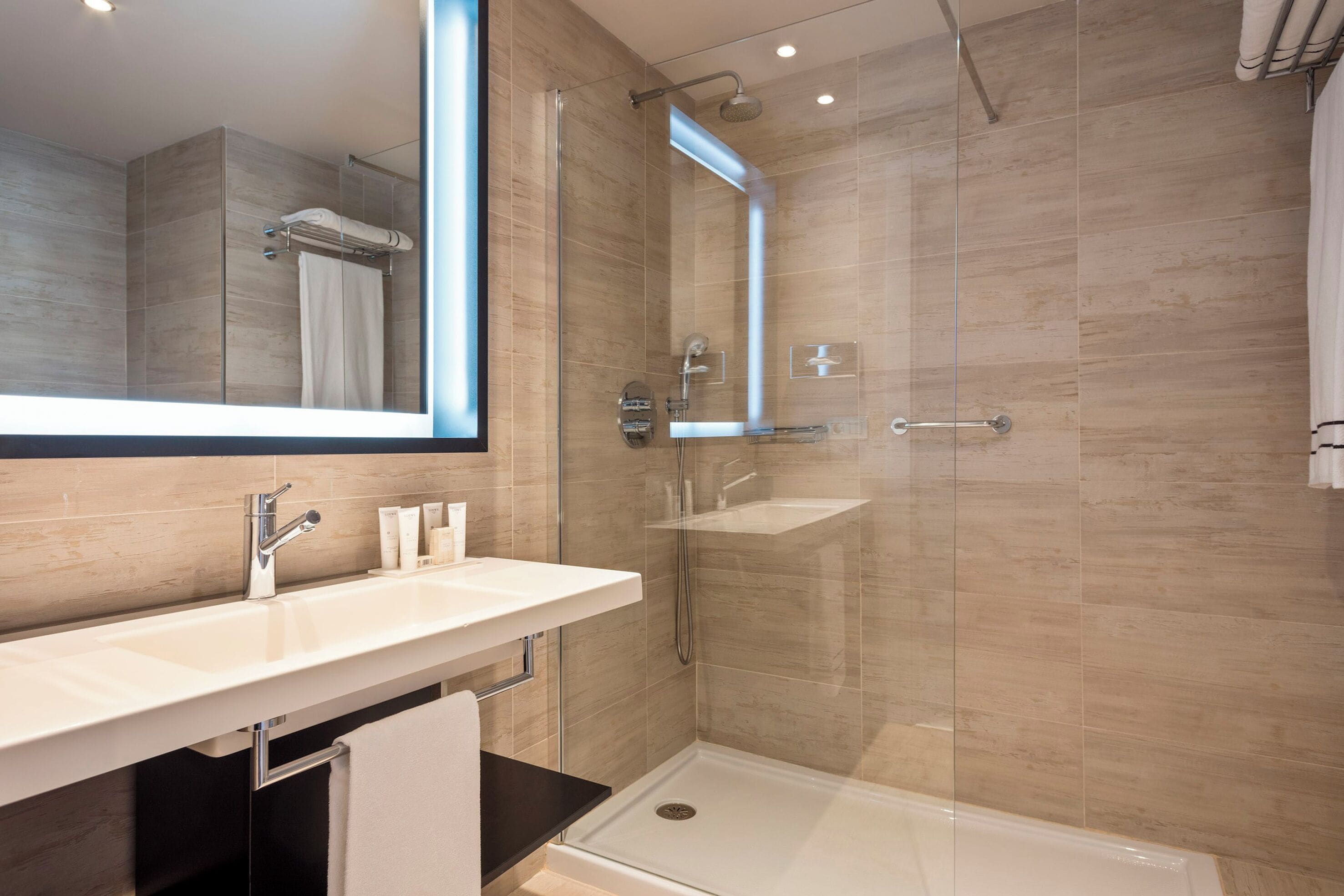 A modern bathroom with a glass shower enclosure, a white sink, and a large mirror.