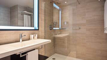 A modern bathroom with a glass shower enclosure, a white sink, and a large mirror.