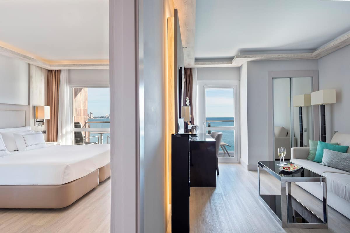 Een moderne hotelkamer met een bed, een bureau en een bank. Er is uitzicht op de stad door het raam.
