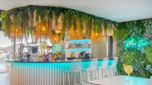 A bar area with a neon sign reading "Blue Bar," surrounded by lush greenery and white chairs. - The Level at Melia Alicante - Adults Only (Alicante)