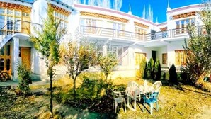 Ein zweistöckiges Gebäude mit Balkon und Garten, einschließlich Sitzgelegenheiten.