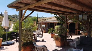 Un espace extérieur aménagé en terrasse, avec des meubles en bois, des plantes en pot et une structure en forme de pergola.