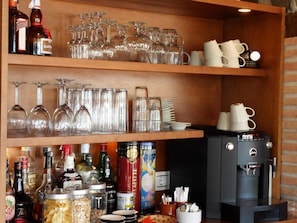 A bar area with shelves holding various bottles, glasses, and a coffee machine. - Bed & Breakfast Casa don Carlos (Alhaurin el Grande)