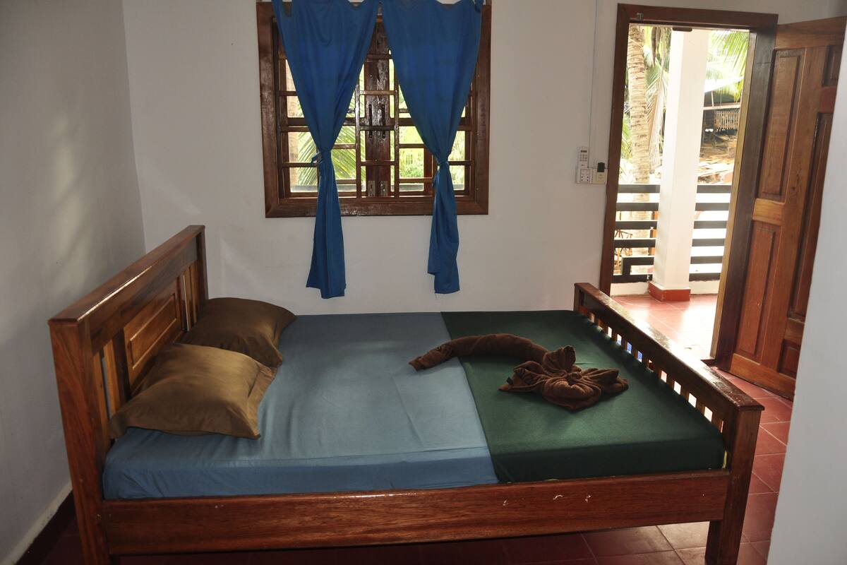 A wooden bed with a blue and green mattress, two pillows, and a brown blanket.